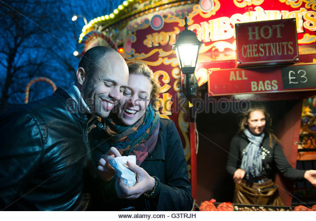 a-couple-standing-in-front-of-a-vendor-selling-hot-chestnuts-on-the-g3trjh